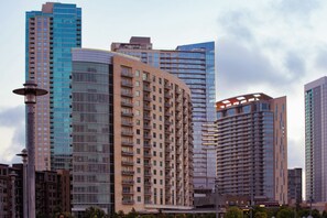 A modern high-rise building with multiple floors, large windows, and a curved facade. - Accessible 2BR Suite | Free Daily Breakfast & Pool (Austin)