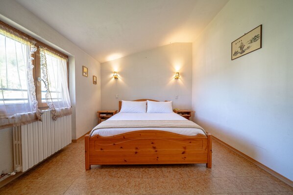 A bedroom with a wooden bed, two bedside tables, a radiator, and two wall-mounted lamps.