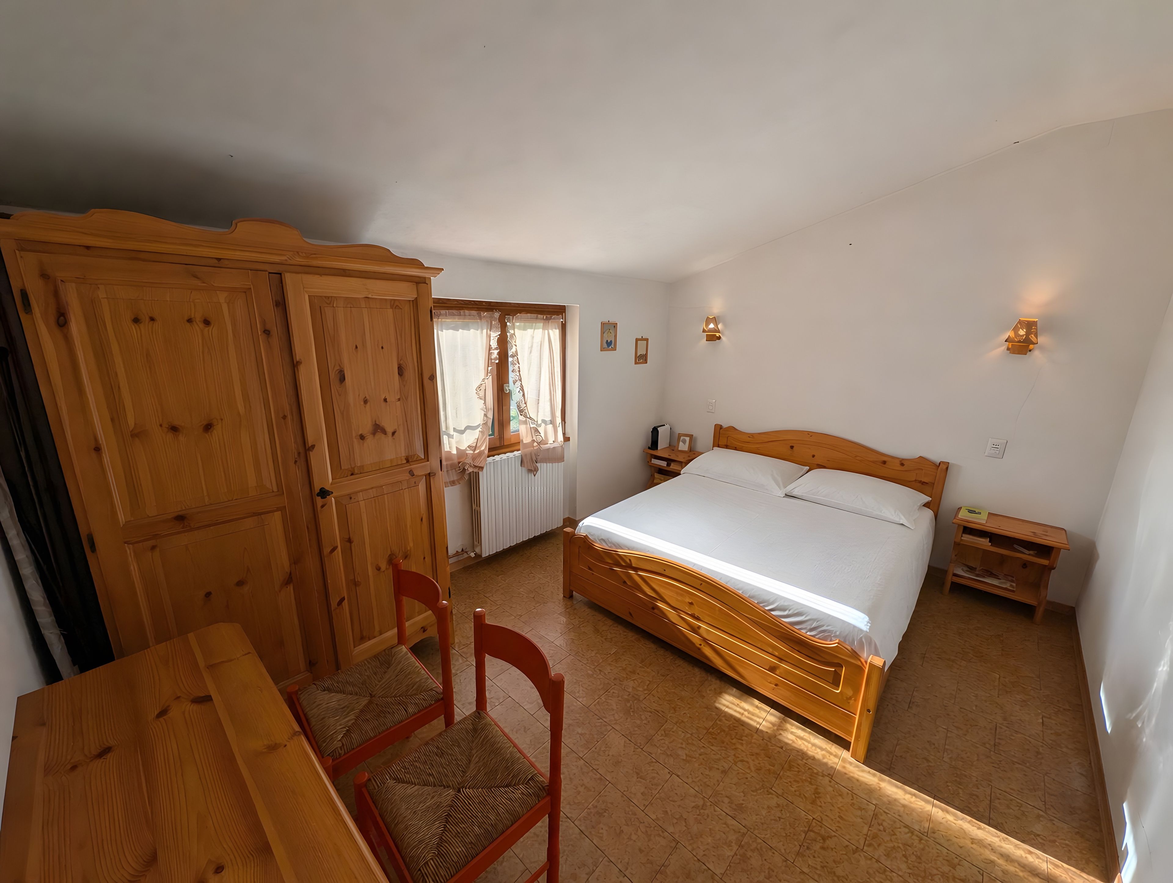 Ein Schlafzimmer mit einem hölzernen Bett, einem Schrank aus Holz, einem Schreibtisch und einem Stuhl.
