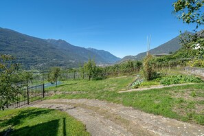 Paisaje rural con cielo despejado, un río y montañas al fondo.