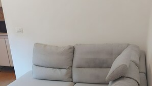 A grey sofa with a glass coffee table in a room with a white wall and wooden flooring. - Ca' Raul · Nestled among the Valtellina vineyards (Poggiridenti)