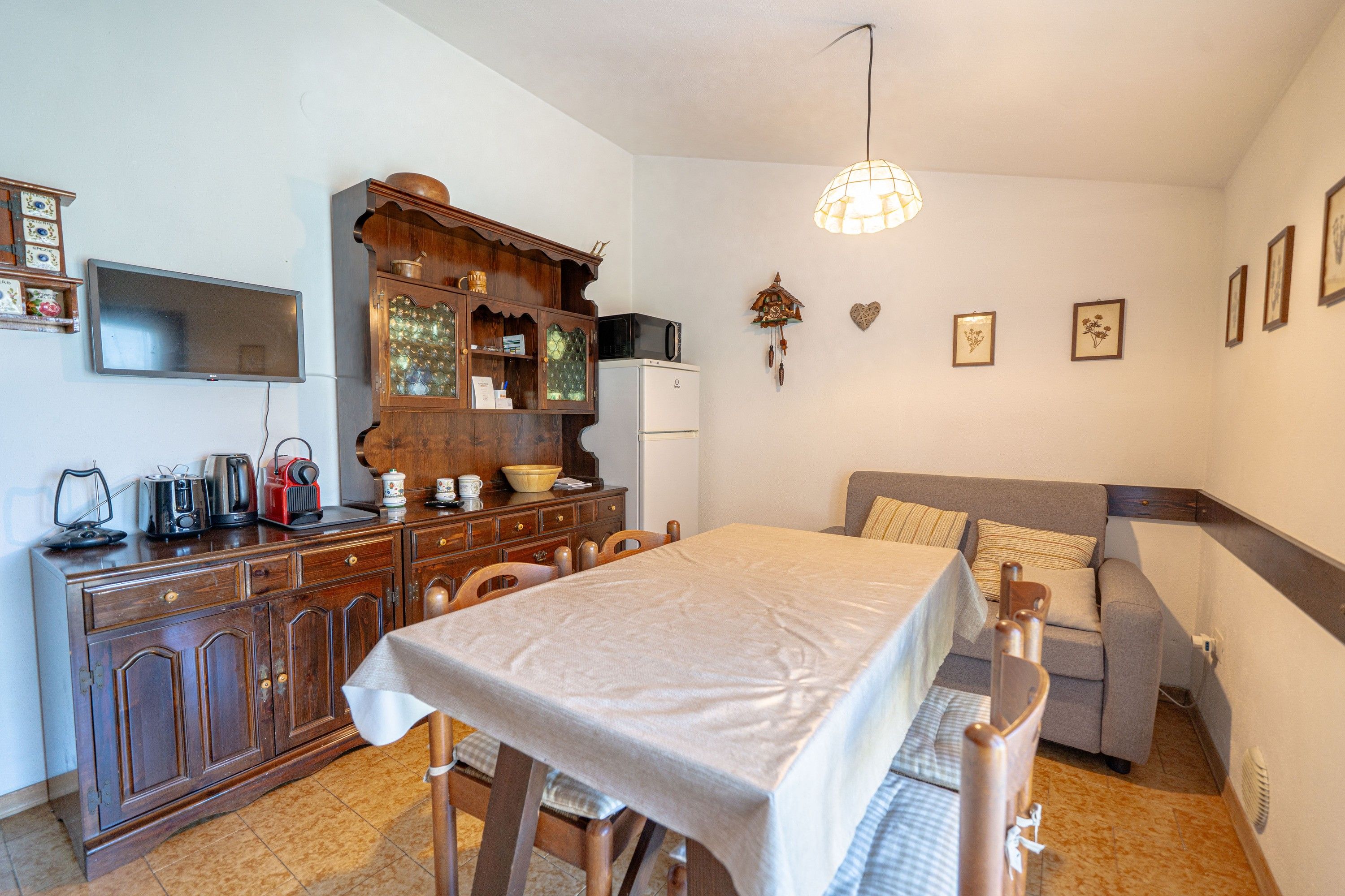 Een knus woongedeelte met een eettafel, een bank, een kitchenette en een televisie.