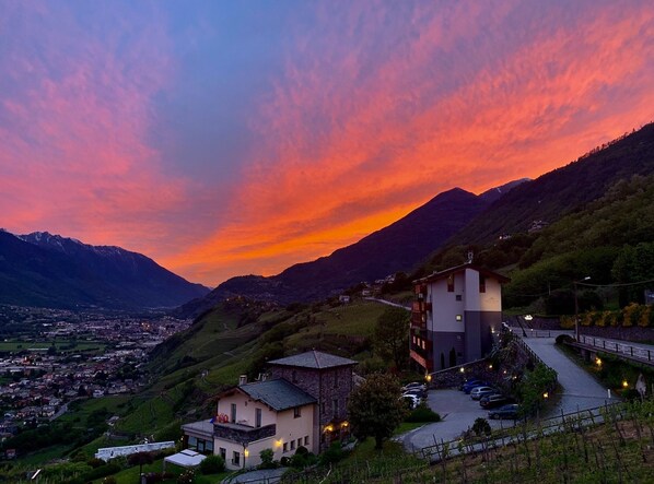 Eine Berglandschaft bei Sonnenuntergang, eine Stadt im Tal und ein Gebäude mit befestigter Auffahrt.
