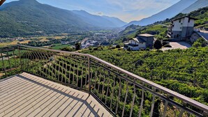 A balcony with a view of a mountainous landscape, a vineyard, and a small building. - Between Vineyards and Peaks · 2 bedrooms, view of the vineyards (Poggiridenti)