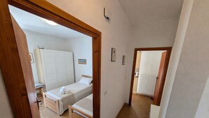 A bedroom with two beds, a wooden floor, and a bathroom visible through an open door. - Between Vineyards and Peaks · 2 bedrooms, view of the vineyards (Poggiridenti)