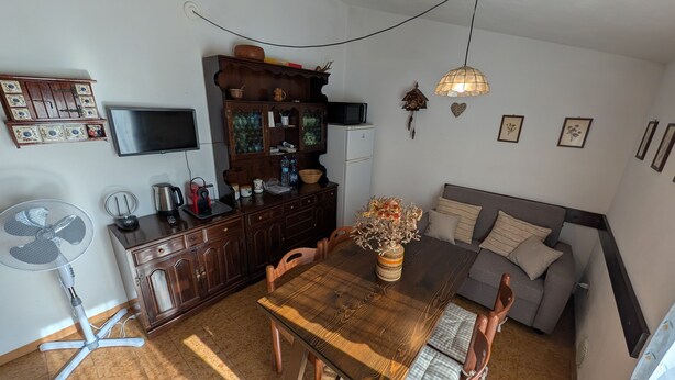 A compact living space with a dining table, a sofa, a TV, and a fan. - Between Vineyards and Peaks · 2 bedrooms, view of the vineyards (Poggiridenti)