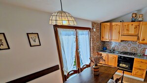 A dining area with a wooden table and chairs, a pendant light, and a view into the kitchen. - Between Vineyards and Peaks · 2 bedrooms, view of the vineyards (Poggiridenti)