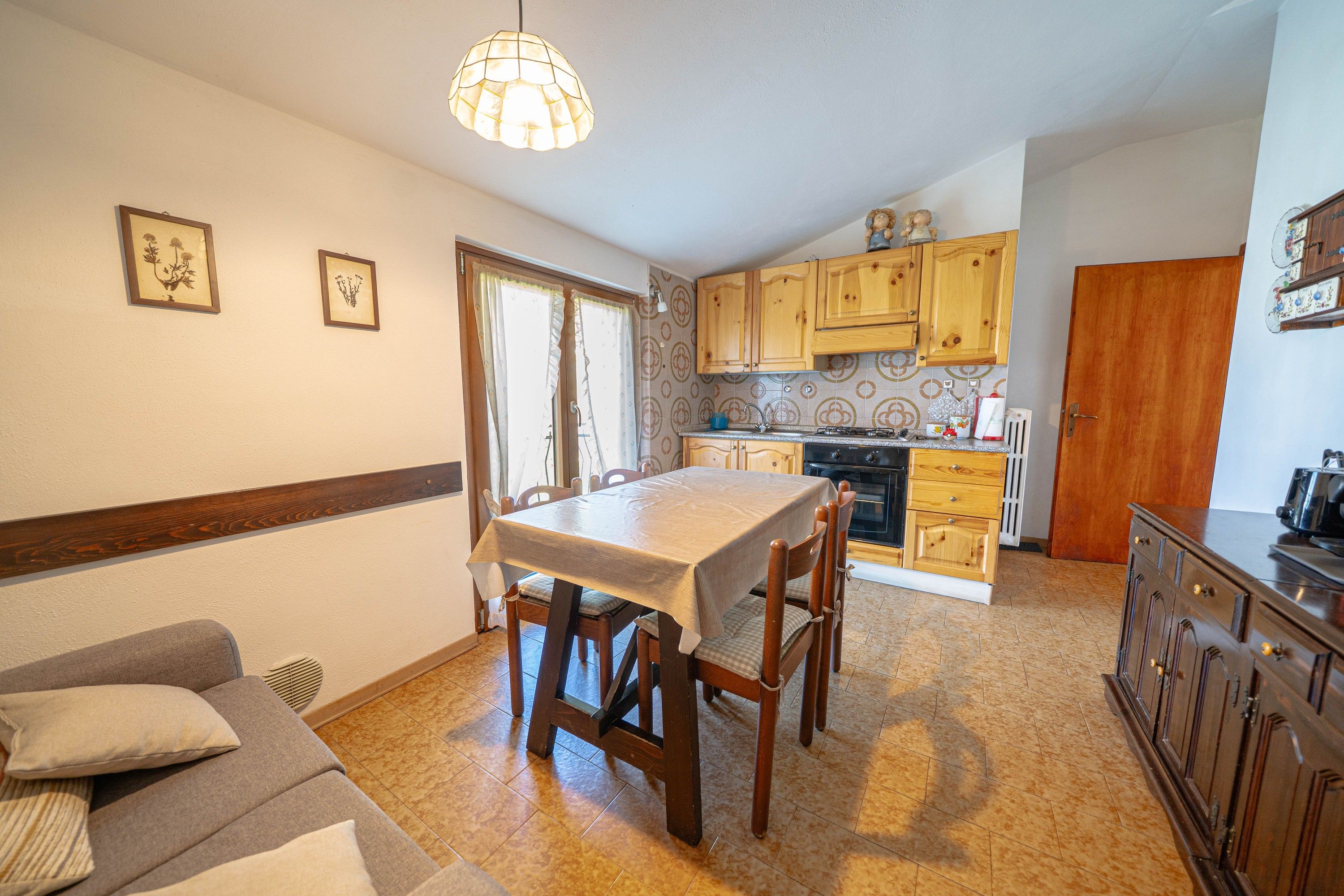 A compact kitchen with wooden cabinets, a dining table, and a sofa.