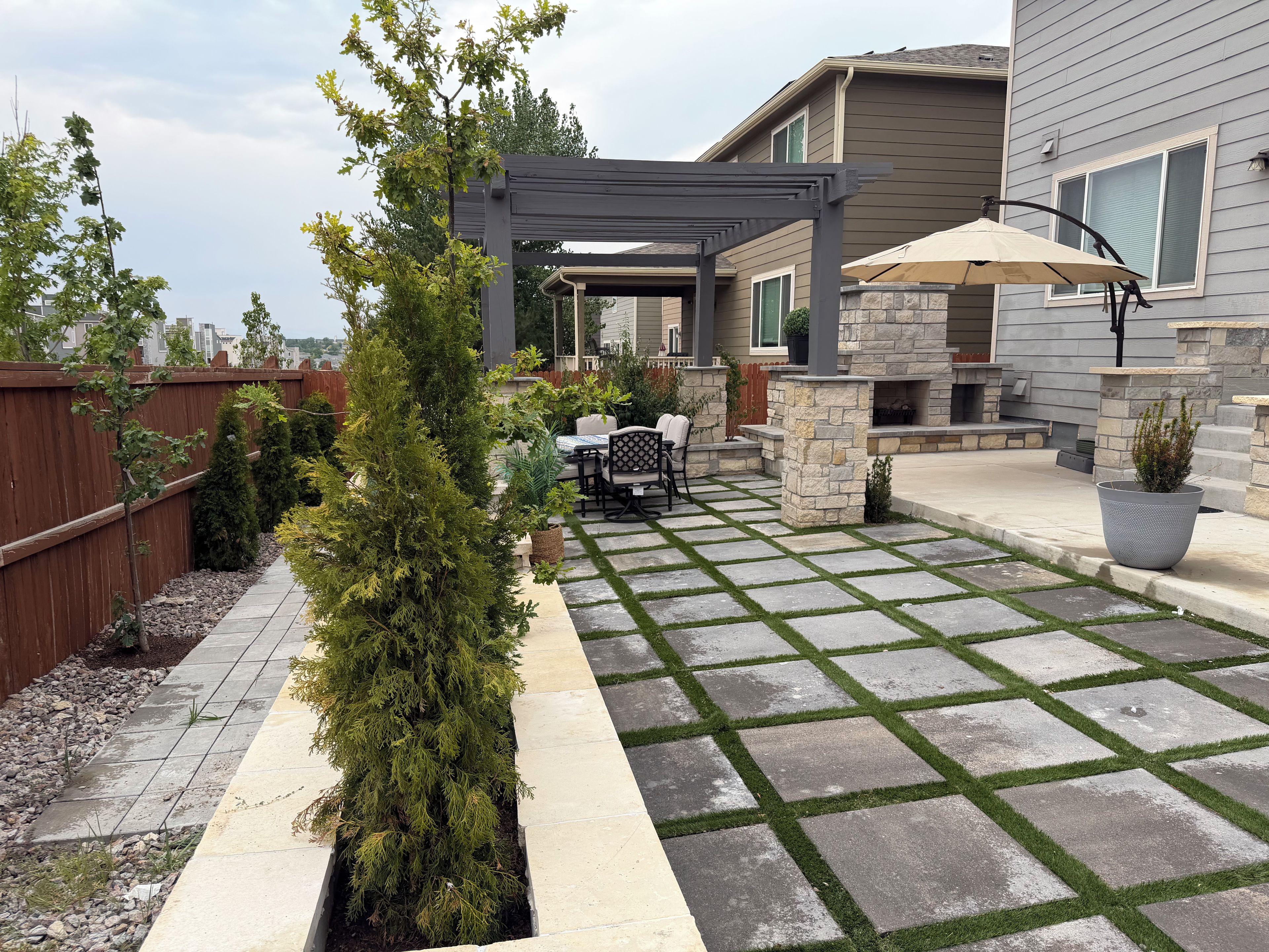 A patio with a pergola, outdoor furniture, and a stone fireplace.