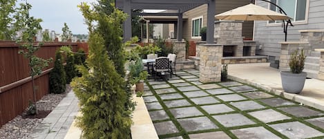 A patio with a pergola, outdoor furniture, and a stone fireplace.