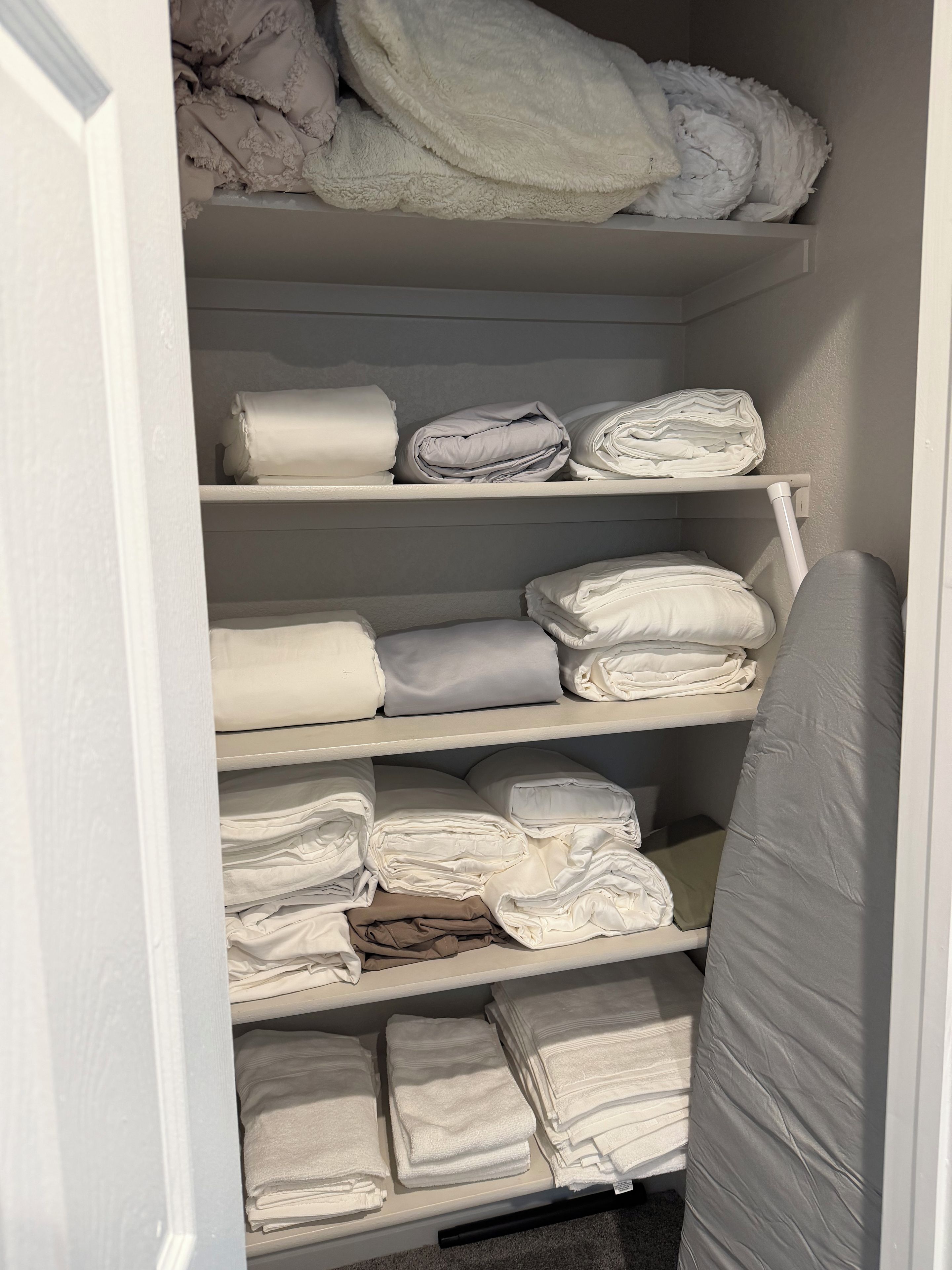 A storage closet with multiple shelves holding folded towels and linens.