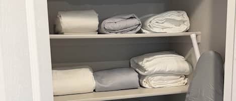 A storage closet with multiple shelves holding folded towels and linens.