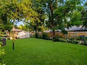 A well-maintained backyard with a lawn, trees, and a wooden fence. - Spacious 3 Bedroom East Dallas Retreat (Dallas)