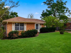 A single-story house with a brick facade, a sloped roof, and a well-maintained lawn. - Spacious 3 Bedroom East Dallas Retreat (Dallas)