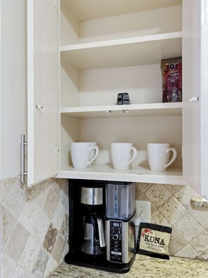 A kitchen with a coffee maker, a coffee bag, and white cups on shelves. - Spacious 3 Bedroom East Dallas Retreat (Dallas)