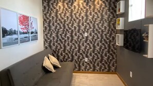 Uma sala de estar moderna com um sofá cinzento, papel de parede estampado e uma pequena mesa de vidro.