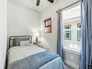 A bedroom with a bed, bedside lamp, window with curtains, and a wall-mounted artwork. - Modern City Retreat | 3BR + Garage (Dallas)