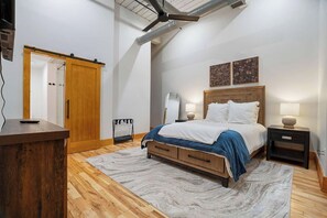 A bedroom with a bed, bedside tables, a wooden desk, a wardrobe, and a ceiling fan. - Historic Loft, Sleeps 4, Near Downtown Knoxville (Knoxville)