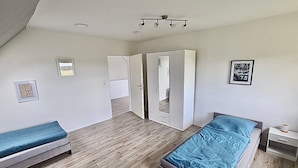 Une chambre avec deux lits, une armoire et un luminaire fixé au plafond.