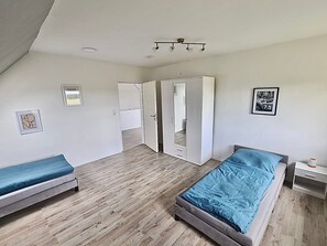 Un dormitorio con dos camas, un armario y una lámpara en el techo.