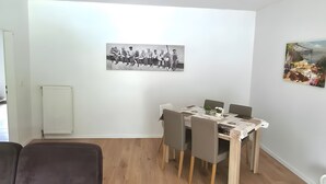 A modern living room with a sofa, dining table, and chairs. - Apartment 'Am Moor' with Private Terrace, Garden, and Wi-Fi (Beverstedt)
