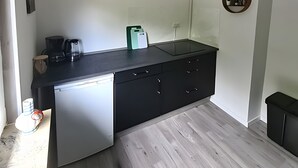 Une cuisine compacte équipée d’un lave-vaisselle, d’une machine à café et d’un petit plan de travail.