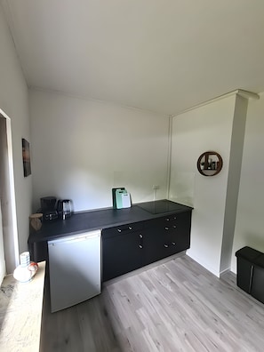 Una cocina funcional con lavavajillas, cafetera y una pequeña encimera.