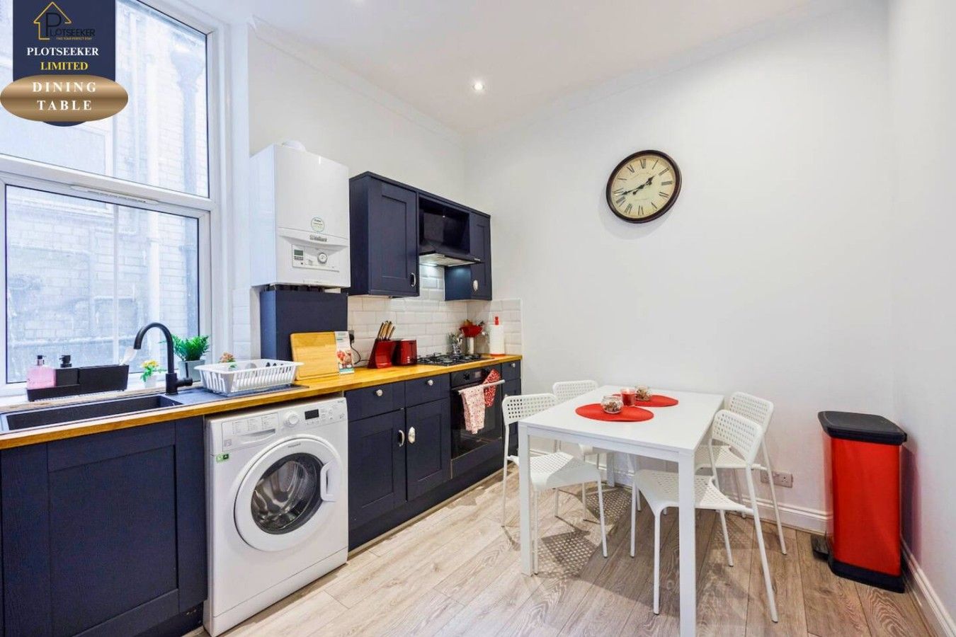 A compact kitchen with a dining area, a washing machine, and a dining table with chairs.