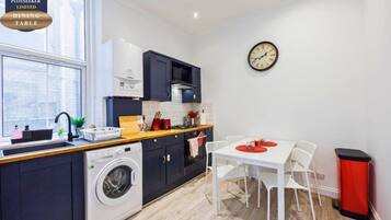 A compact kitchen with a dining area, a washing machine, and a dining table with chairs.