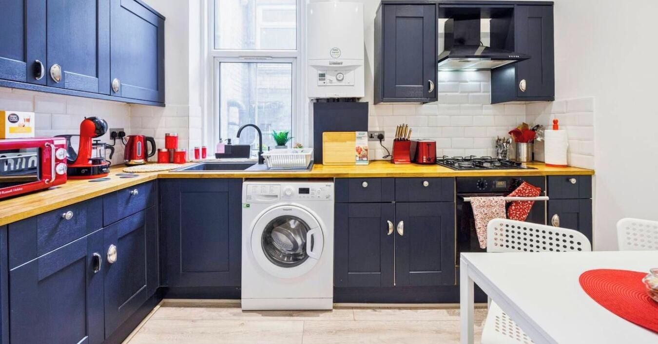 A compact kitchen with a washing machine, a coffee maker, and a toaster.