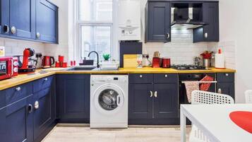 A compact kitchen with a washing machine, a coffee maker, and a toaster.