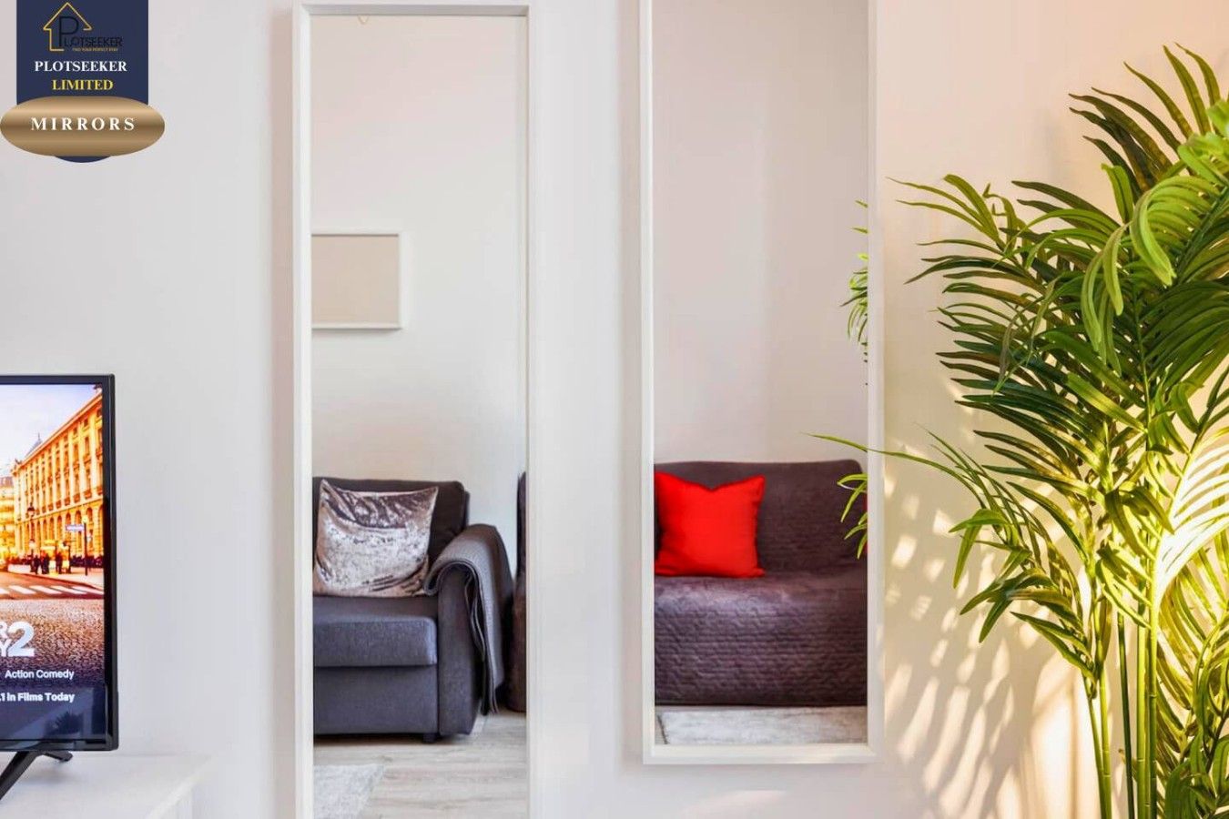 A living room with a television, a sofa, and a potted plant.