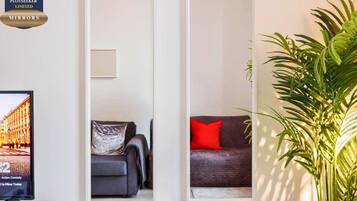 A living room with a television, a sofa, and a potted plant.