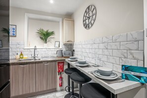 Een moderne keuken met marmeren tegels, een klok, een brandblusser en een welkomstbord.