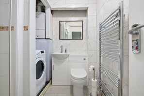 A compact bathroom with a washing machine, toilet, sink, and towel rack. - Stylish 5BR Oxford Cooper House,Sleep 11, Parking (Oxford)
