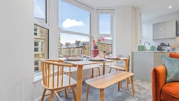 A modern kitchen with a dining area, large windows, and a view of the cityscape.