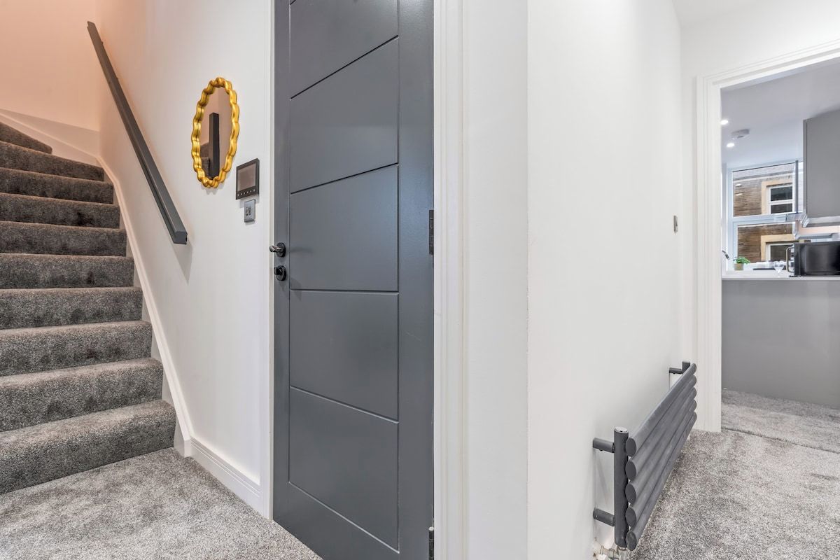 A staircase leading to a door with a security panel and a wall-mounted light fixture.
