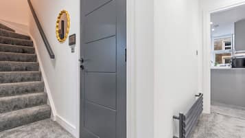 A staircase leading to a door with a security panel and a wall-mounted light fixture.