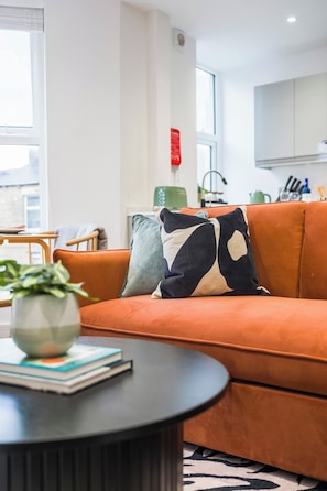 Una sala de estar moderna con un sofá, una mesita redonda y una planta verde.