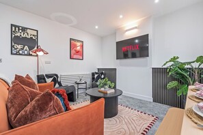 A modern living room with a sofa, a coffee table, a TV, and a plant. - Coastal retreat near Morecambe Bay and promenade (Heysham)