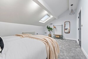 Ein Schlafzimmer mit einem Bett, einem Oberlicht, einem Spiegel, einer Heizung und einer Pflanze.