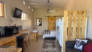 Una habitación con cama, sofá, televisión, escritorio de madera y espejo.