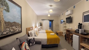 Habitación de hotel con cama, sofá, escritorio con computadora, televisor y un cuadro en la pared.