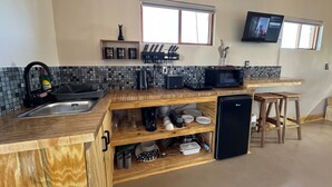Una cocina compacta con un lavamanos, microondas y un refrigerador pequeño.