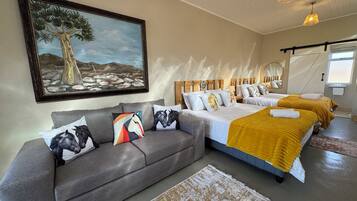 A bedroom with a large bed, a sofa, and a painting on the wall.