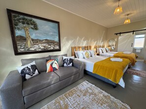 A bedroom with a large bed, a sofa, and a painting on the wall.