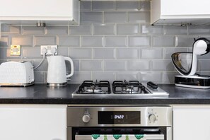 A modern kitchen with a gas stove, a toaster, and a kettle. - West Kensington 2BR | Steps to Tube | Sleeps 7 (Greater London)