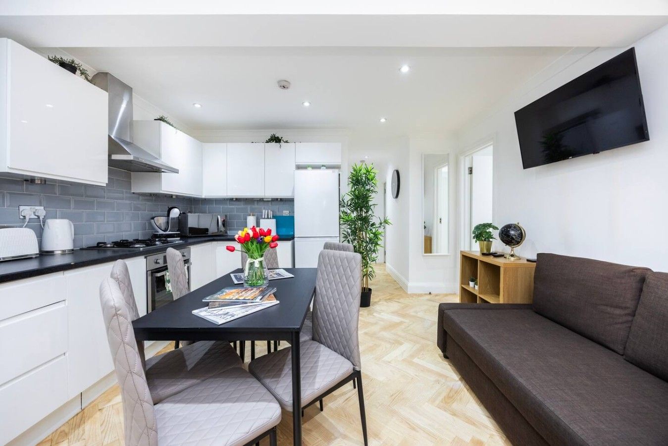 A modern apartment with a dining area, kitchen, and living space.