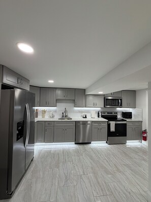 Una cocina moderna con electrodomésticos de acero inoxidable, armarios grises y piso de mármol.