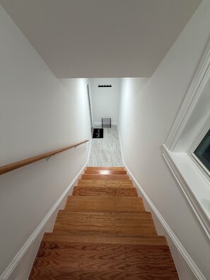 Una escalera con escalones de madera que conduce a una plataforma con un letrero negro fijado a la pared.